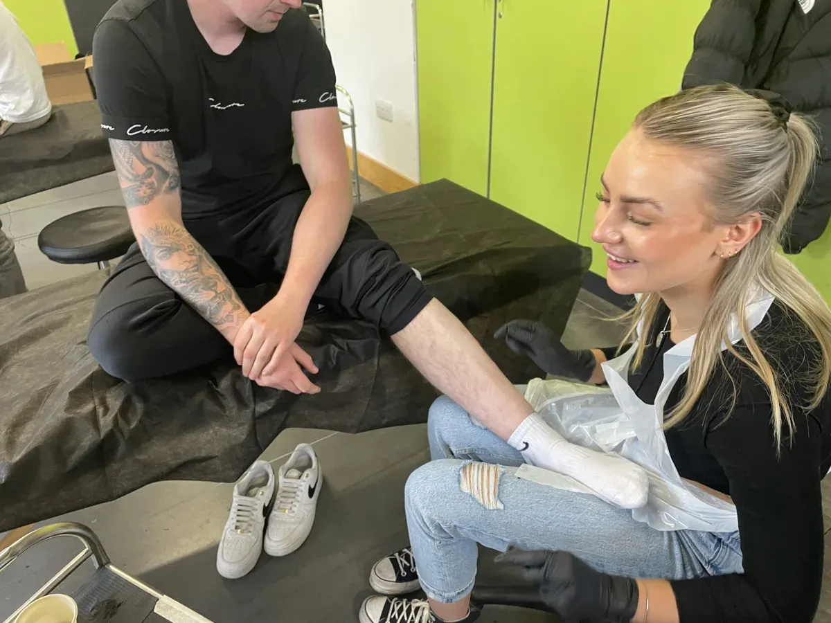 A tutor supervising a student during a tattoo session